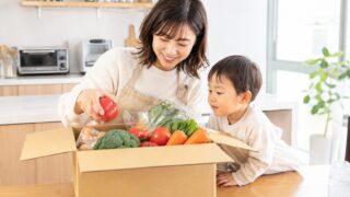 無添加の食材宅配で届いた新鮮な野菜を子どもと一緒に開けるママ