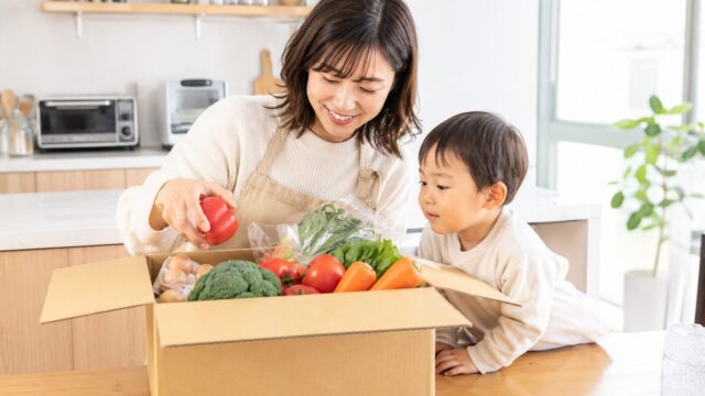 無添加の食材宅配で届いた新鮮な野菜を子どもと一緒に開けるママ