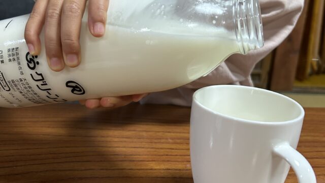 子どもがグリーンコープのノンホモ牛乳をカップに次いでいるところ