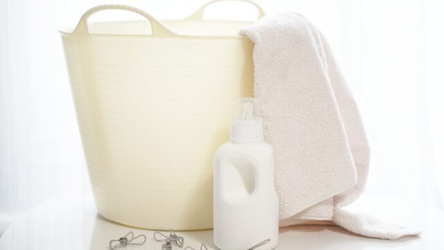 白いタオルと洗濯洗剤、洗濯カゴの写真