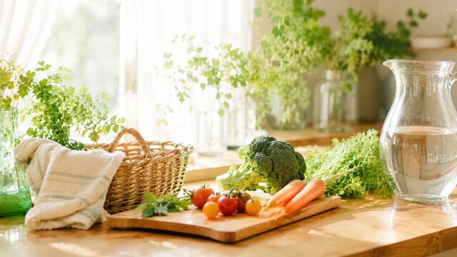 朝の光が差し込む台所に新鮮な野菜と籐の籠が並ぶ、ナチュラルで安心感のある食卓のイメージ